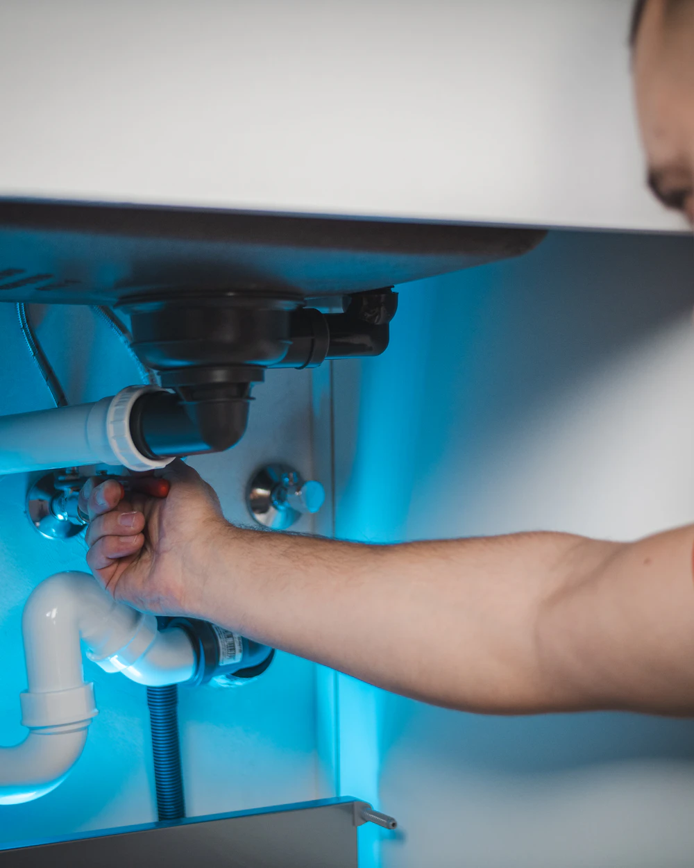 A plumber working on a pipe inside a wall